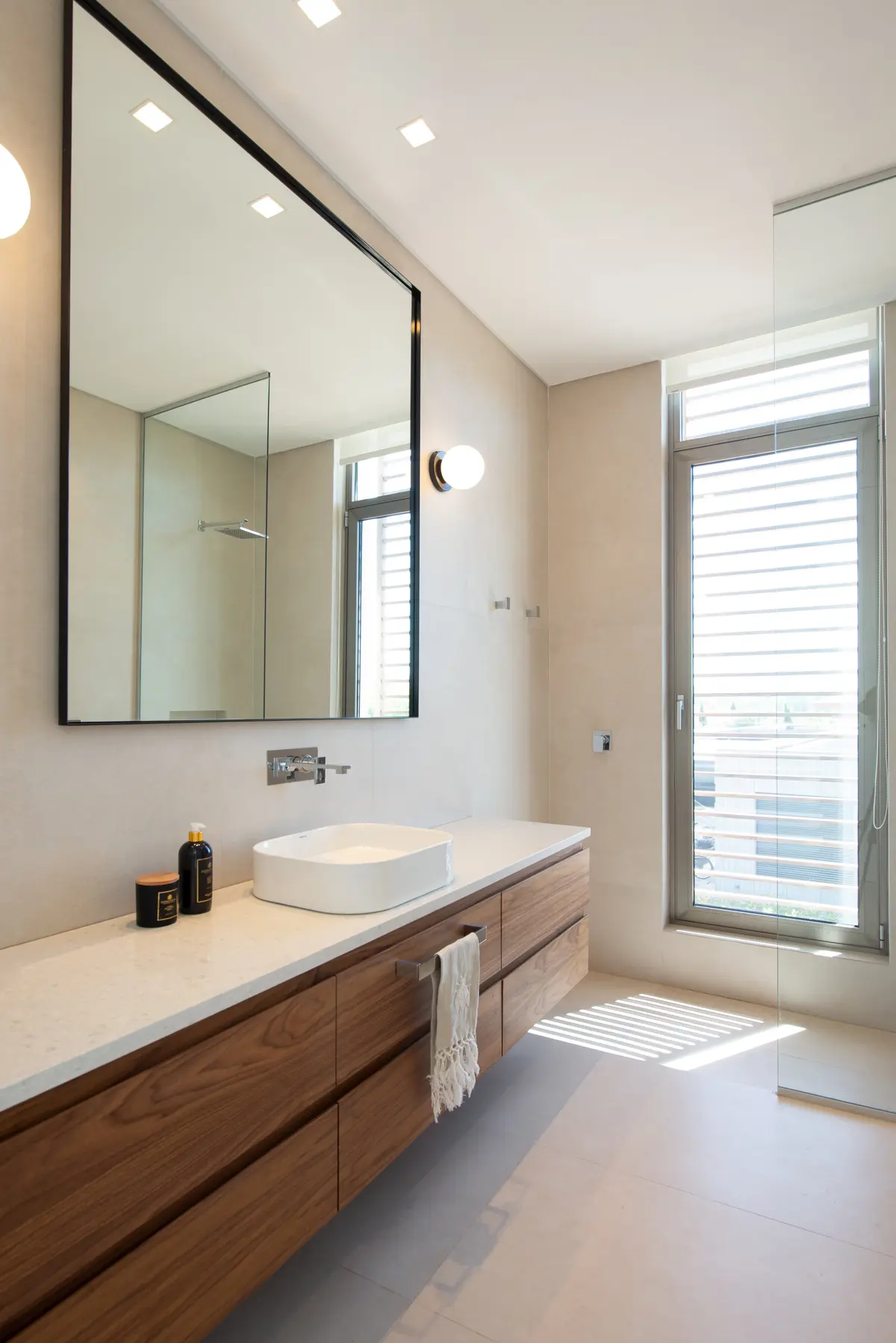 Baño moderno con mueble flotante de madera y gran espejo — proyecto Casa AA, por Estudio Junor, en Pilar